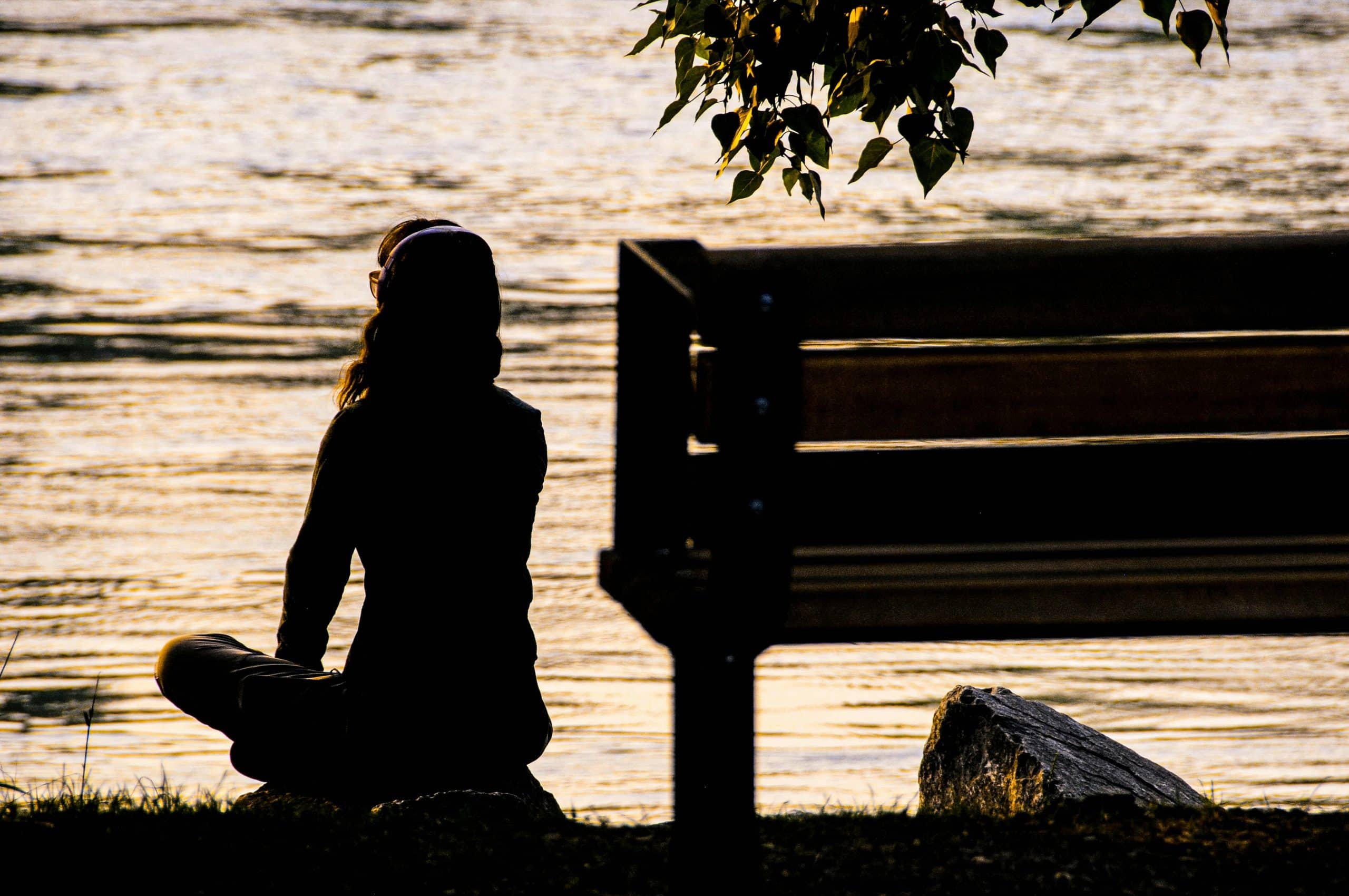Person sitting peacefully on a bench by the water